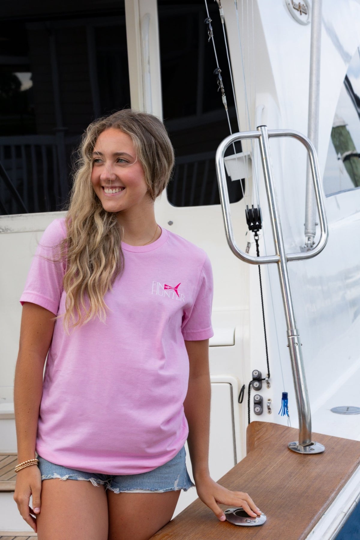 Woman wearing the Fin Hunter Tail Pink Camo T-Shirt on a fishing boat, front view