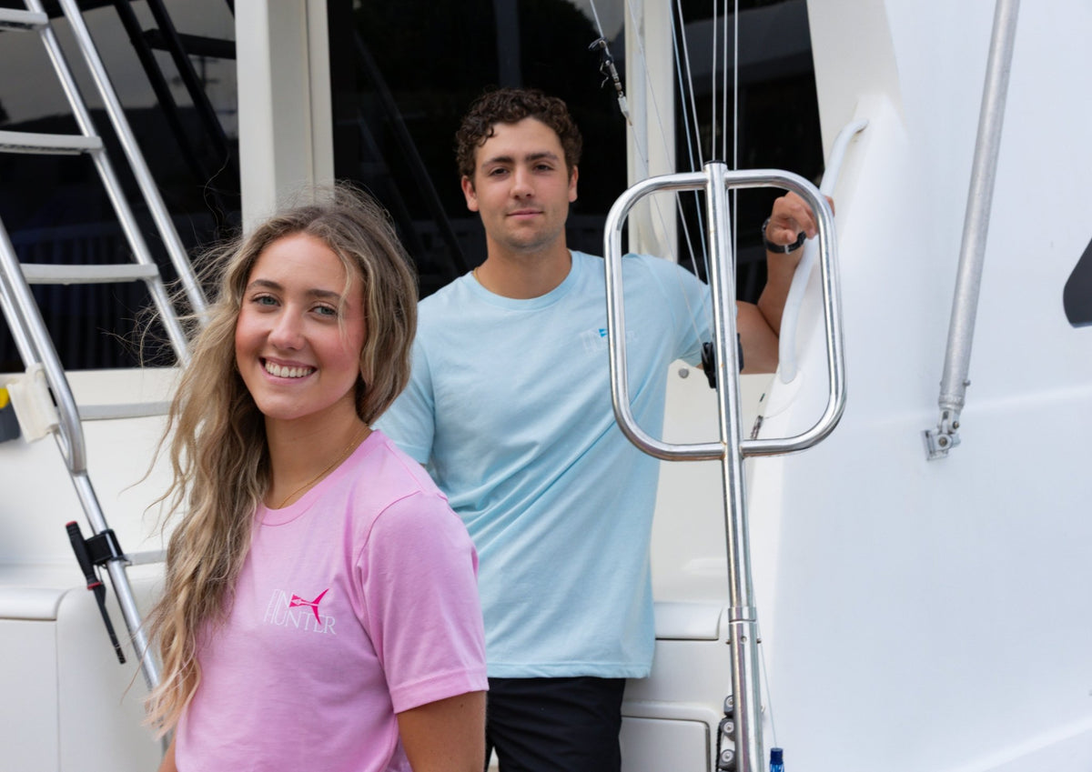 Woman in the Pink Camo T-Shirt and man in the Blue Camo T-Shirt beside a fishing boat