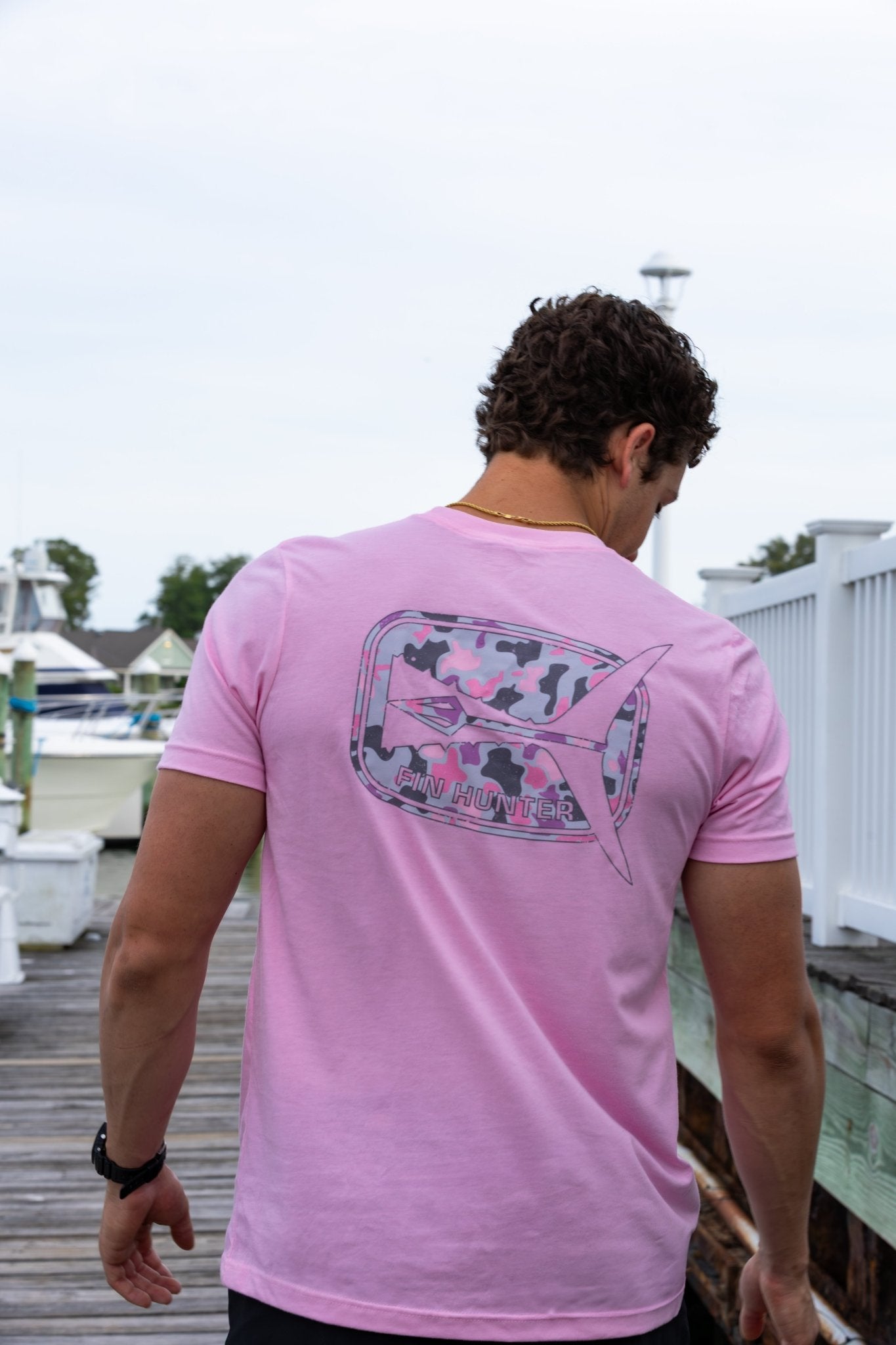 Man wearing the Fin Hunter Tail Pink Camo T-Shirt, back view showing the tail graphic