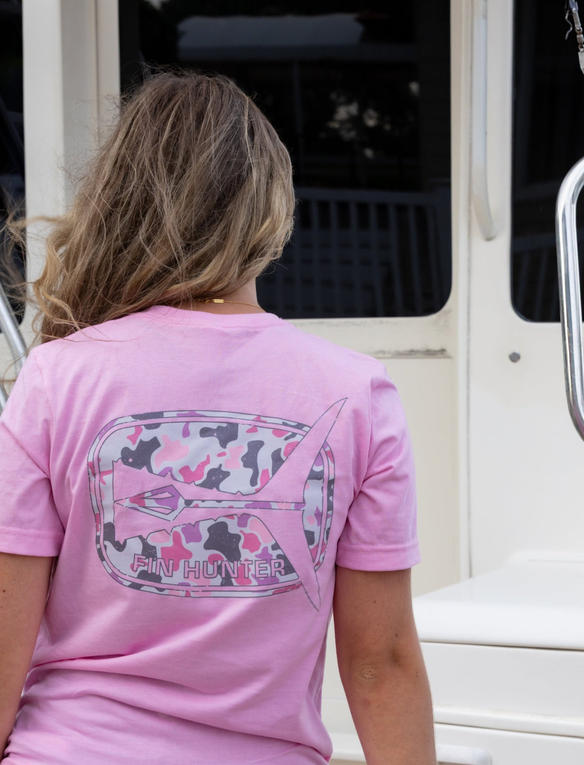 Woman wearing the Fin Hunter Tail Pink Camo T-Shirt, back view showing the tail graphic