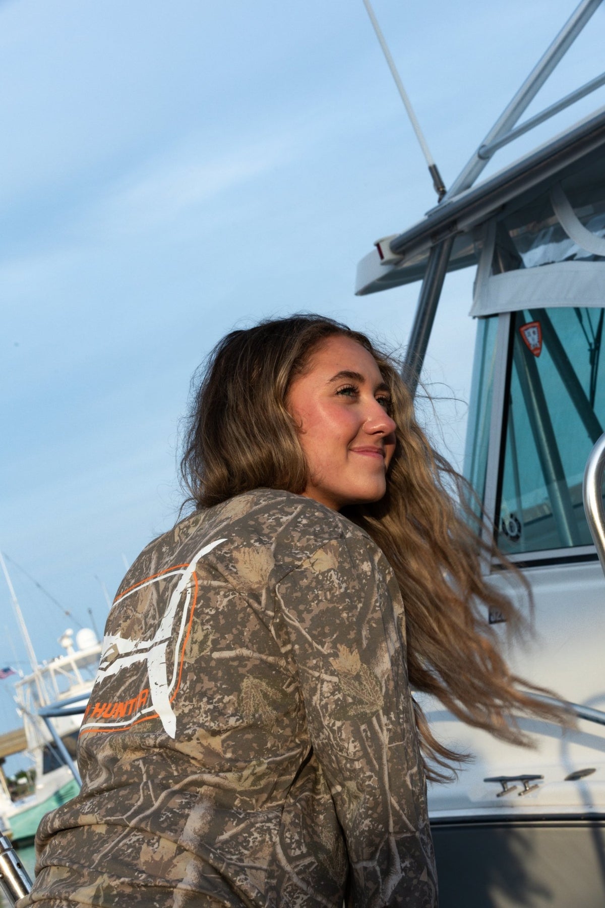 Woman wearing the unisex Fin Hunter Tuna Tail Deadwood Camo Long Sleeve, back view